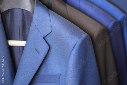 close up luxurious style gentlemen suit row, hanging in a closet .