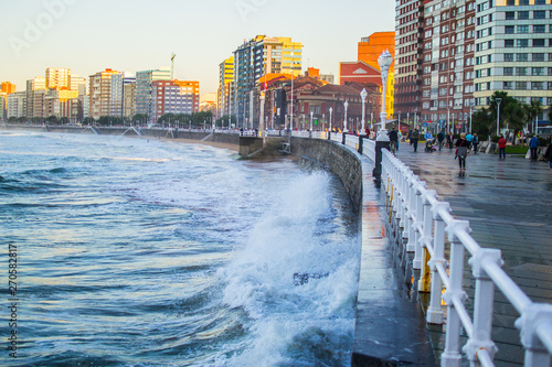 Waves crushing with the wall in San Lorenzo beach in Gijon, Asturias, Spain, with buildings and the promenade at the background © Jesus Barroso