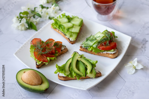 Vegetarian sandwiches with avocado, tomatoes and cucumbers on a light background