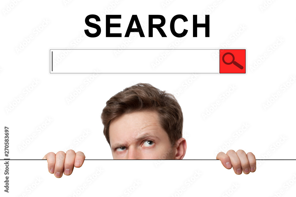 Young man with surprised eyes peeking out from behind billboard on inscription «search Young man with surprised eyes peeking out from behind billboard on inscription «search