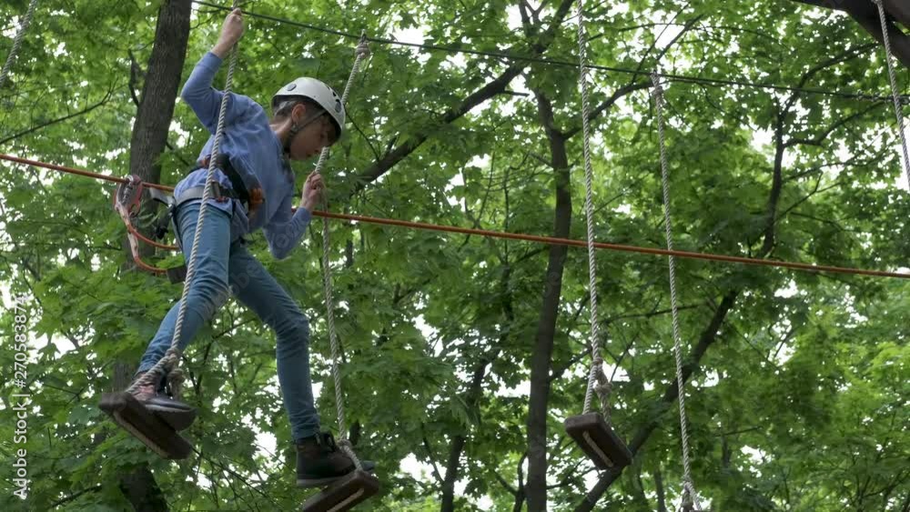 A child in climbing equipment. Young girl in an extreme amusement park on an obstacle course. A child in climbing equipment. Young girl in an extreme amusement park on an obstacle course.