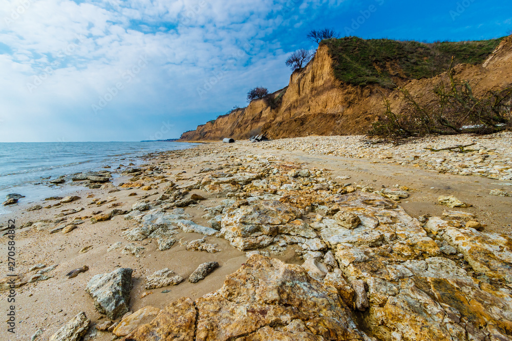 The seashore with limestone boulders and steep clay cliff. Russia, Azov sea, Taganrog bay