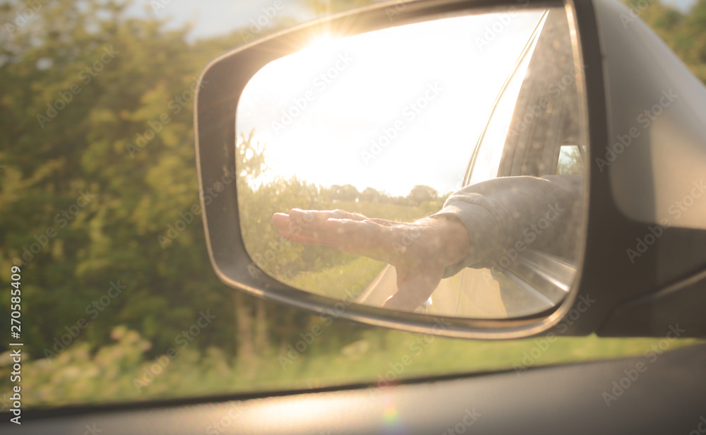 Carefree traveller with hand out passenger side window of car on a road trip Carefree traveller with hand out passenger side window of car on a road trip