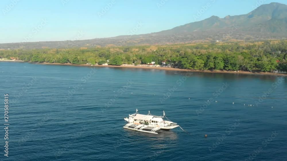 Aerial drone parallax show of a boat in the middle of the ocean near a tropical island Aerial drone parallax show of a boat in the middle of the ocean near a tropical island
