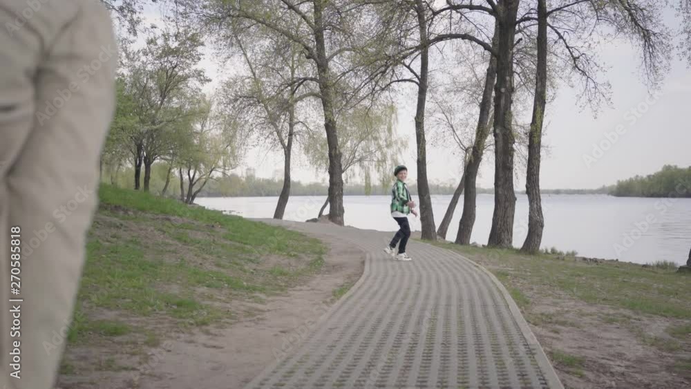 Little boy running from his grandfather in the park, he wants to go to the river. The old man can not follow the boy, he is tired and stopped to catch his breath. Family playing outdoors Little boy running from his grandfather in the park, he wants to go to the river. The old man can not follow the boy, he is tired and stopped to catch his breath. Family playing outdoors