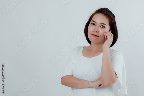 Asian beautiful woman Standing in a white shirt Put the mobile phone attached to the ear to talk to the destination. Prepare to make a call. With a happy smile With a white background © Ekkasit A Siam
