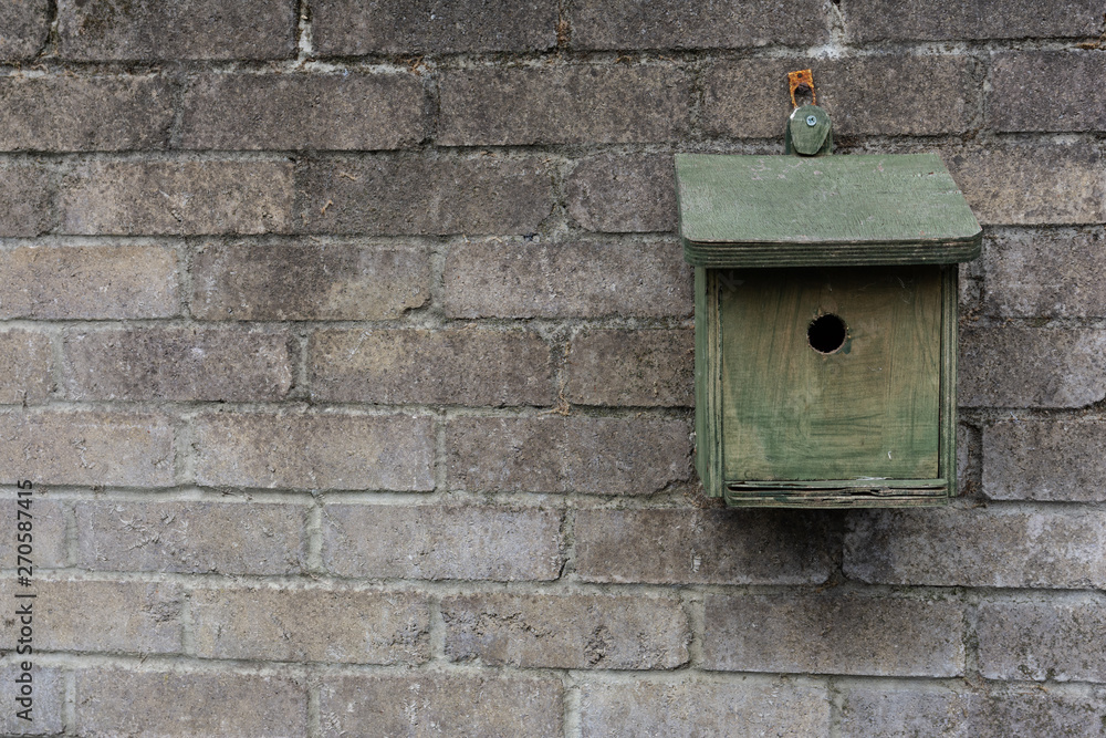 Handmade old wooden bird box against a stone brick wall