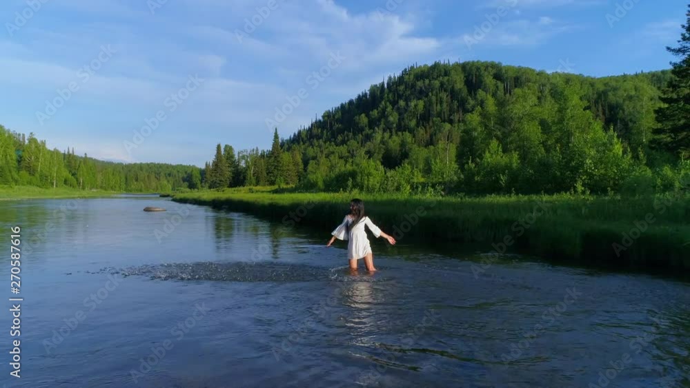 girl walks in the water on a mountain river, arms outstretched, with joy. Asian stands in the river and plays with water. whirlwinds and splashes of water, the girl in the river. slow motion. Aerial girl walks in the water on a mountain river, arms outstretched, with joy. Asian stands in the river and plays with water. whirlwinds and splashes of water, the girl in the river. slow motion. Aerial