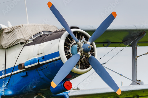 White and blue soviet aircraft biplane Antonov AN-2 at the parking on airfield closeup against cloudy sky