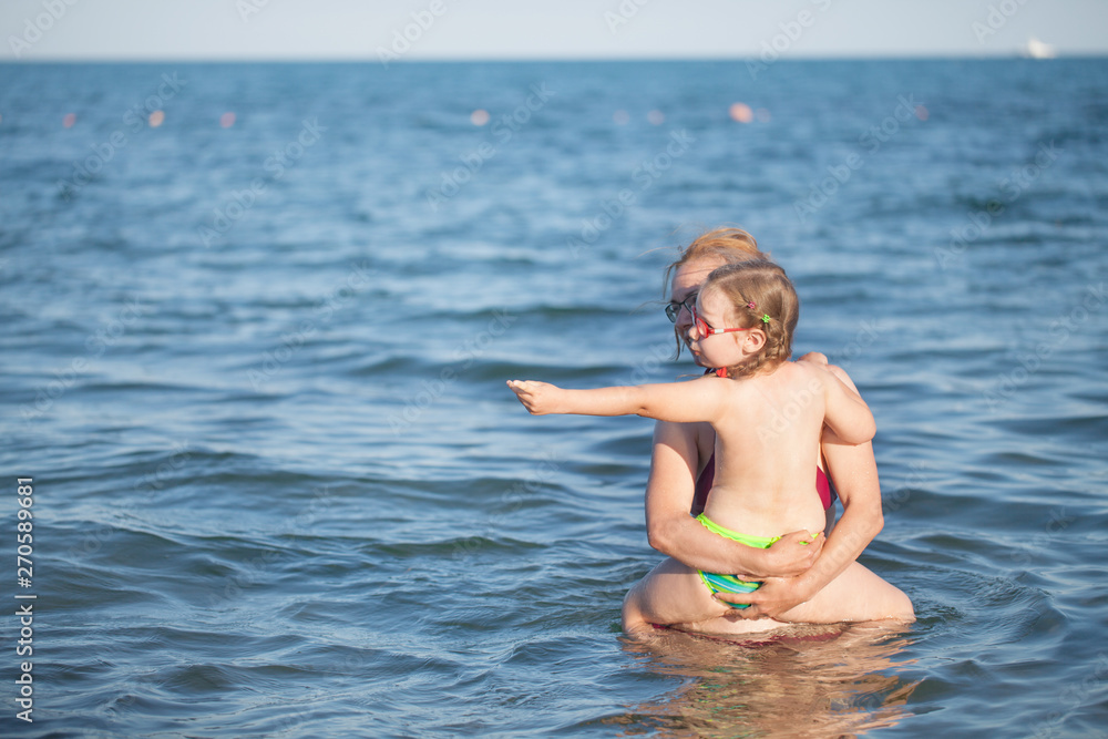 young girl in red glasses and a green bathing suit resting on the sea. childhood and sea air