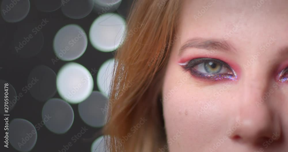 Half face portrait of pretty blonde model with bright make-up watching upwards being dreamy on bokeh background. Half face portrait of pretty blonde model with bright make-up watching upwards being dreamy on bokeh background.