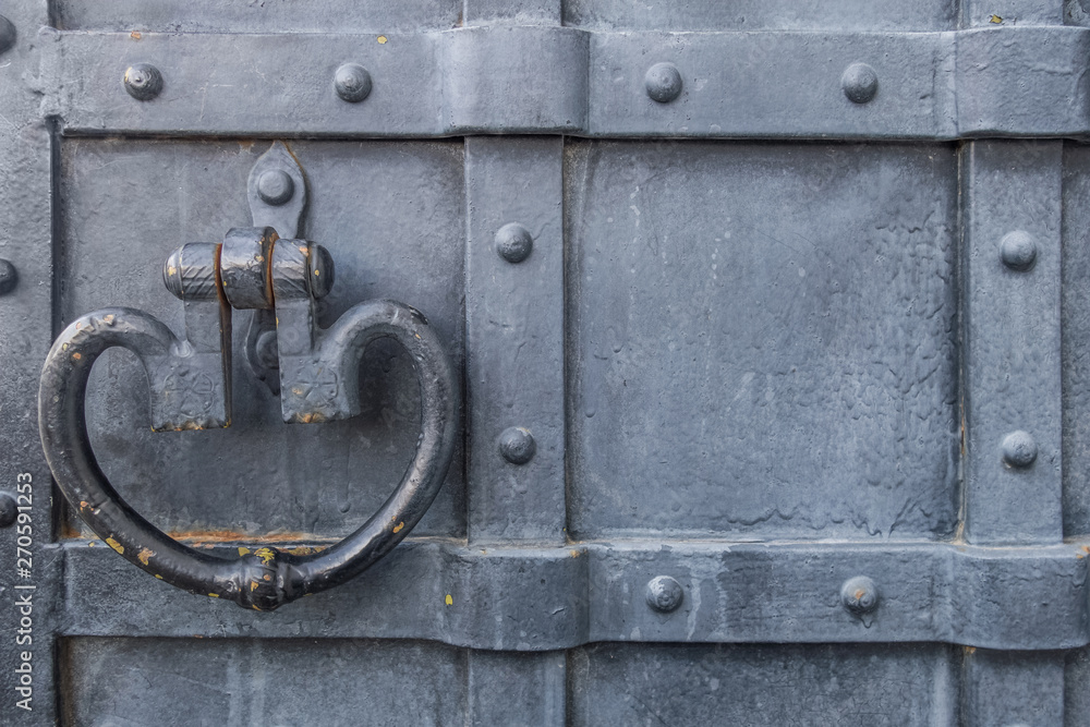 background of old metal upholstered painted in black door with wrought antique handle close up background of old metal upholstered painted in black door with wrought antique handle close up