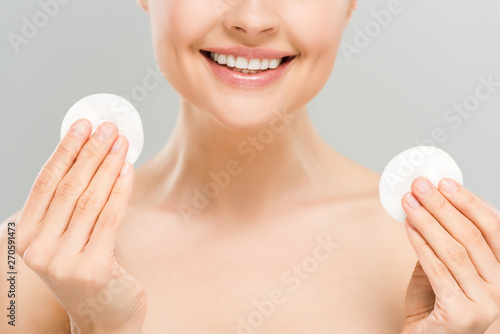 cropped view of happy naked woman holding cotton pads isolated on grey