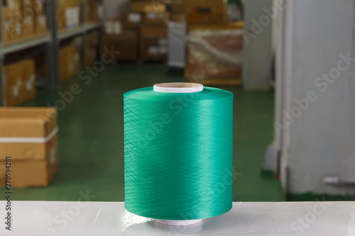 Green thread spool in the warehouse of a textile factory. Thread for knitting production.