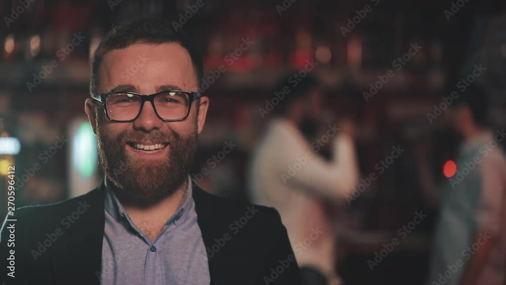 Portrait of smiling attractive man wearing glasses looking at camera in a bar or beer pub. Concept of youth, friendship and resting. Portrait of smiling attractive man wearing glasses looking at camera in a bar or beer pub. Concept of youth, friendship and resting.
