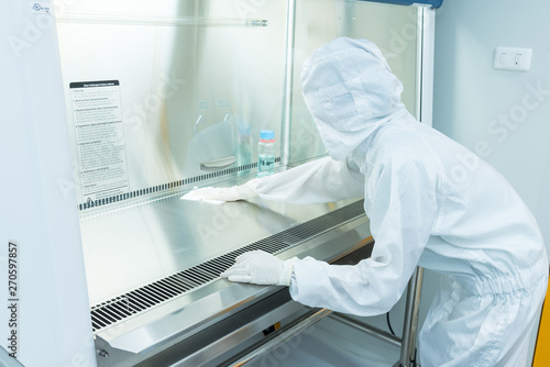 Canvastavla A scientist in sterile coverall gown using alcohol 70% and cleanroom wipes for cleaning Biological safety cabinet(BSC