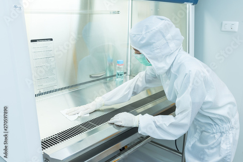 A scientist in sterile coverall gown using alcohol 70% and cleanroom wipes for cleaning Biological safety cabinet(BSC.) photo