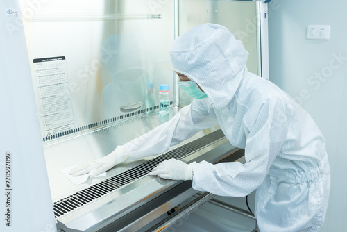 A scientist in sterile coverall gown using alcohol 70% and cleanroom wipes for cleaning Biological safety cabinet(BSC.)