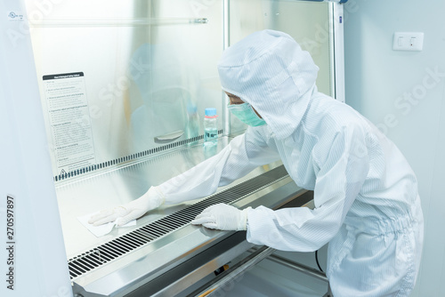Konstfotografi A scientist in sterile coverall gown using alcohol 70% and cleanroom wipes for cleaning Biological safety cabinet(BSC