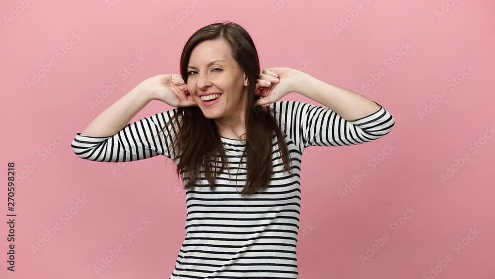 Sleeping beauty brunette young woman in striped shirt wake up in the morning, stretch oneself with hands isolated over pastel pink background in studio. People sincere emotions, lifestyle concept. Sleeping beauty brunette young woman in striped shirt wake up in the morning, stretch oneself with hands isolated over pastel pink background in studio. People sincere emotions, lifestyle concept.