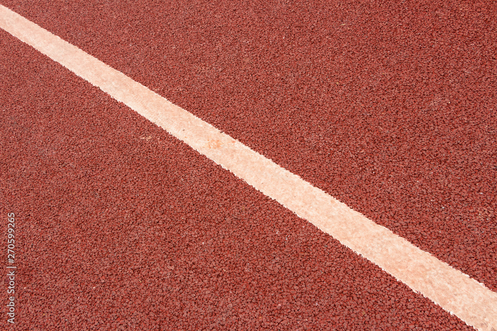 A white dividing diagonal on a red asphalt runway A white dividing diagonal on a red asphalt runway