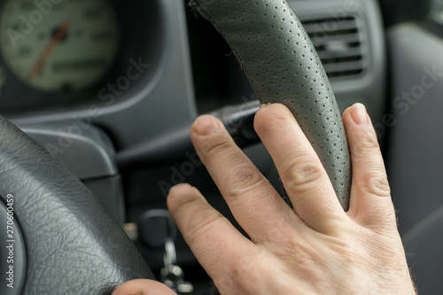 Hand of a man with a missing finger phalanx on the background of the steering wheel and dashboard of the car