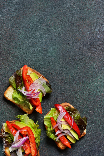 Crispy toast bread with salad, pepper, onion and avocado. View from above. photo