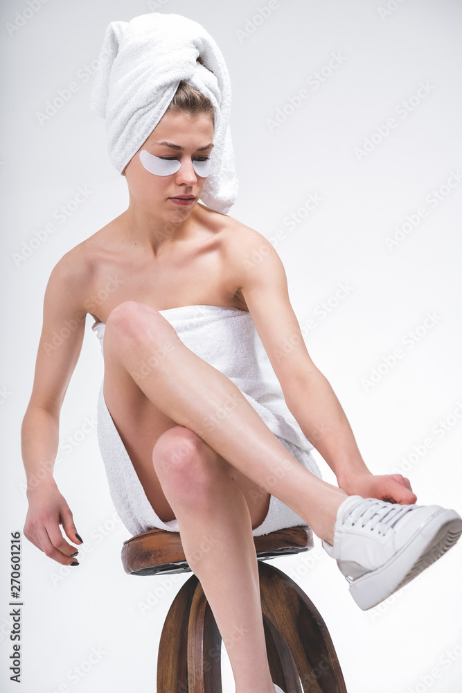 naked young girl wrapped in a towel, sitting on in sneakers. Stock Photo | Adobe Stock