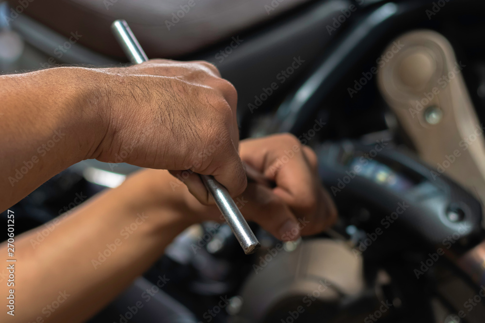 Image is Close up,People are repairing a motorcycle Use a wrench and a screwdriver to work.