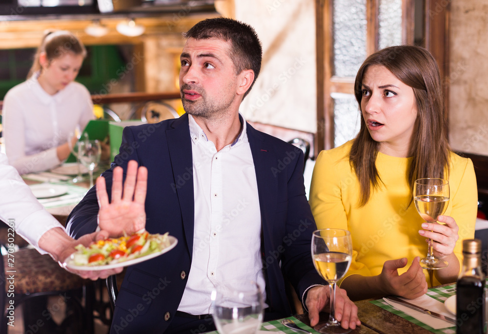 Man is refusing salad in time dining with woman