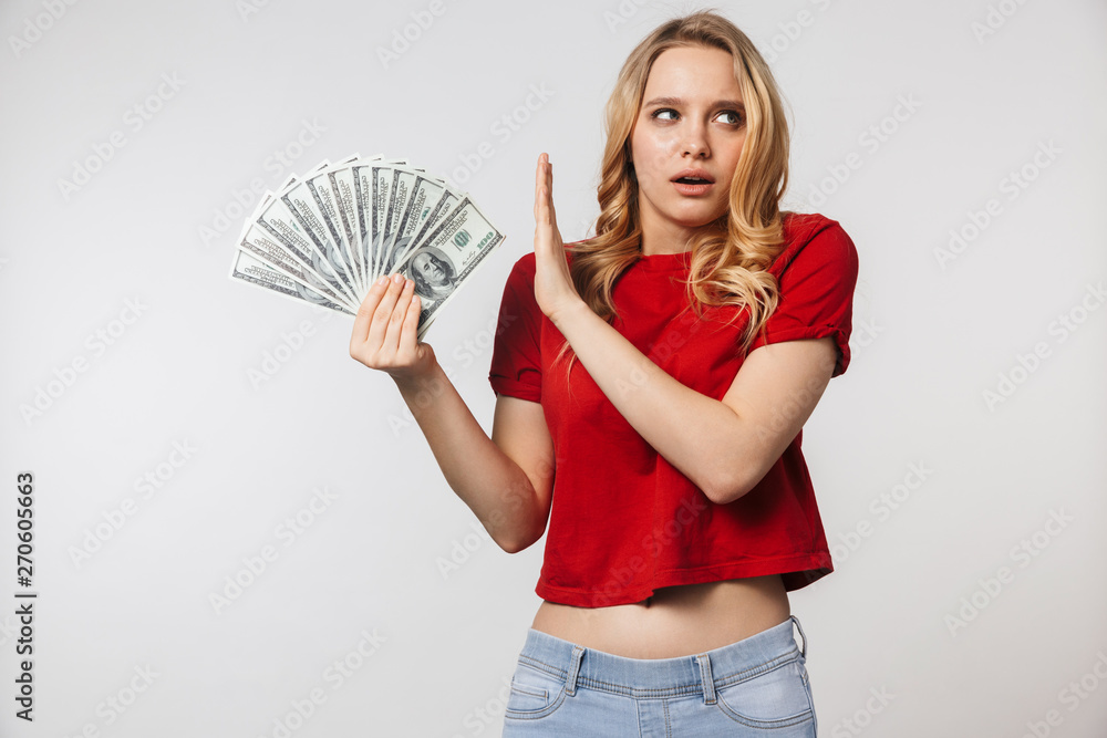 Displeased young pretty beautiful woman posing isolated over white wall background holding money make stop gesture. Displeased young pretty beautiful woman posing isolated over white wall background holding money make stop gesture.