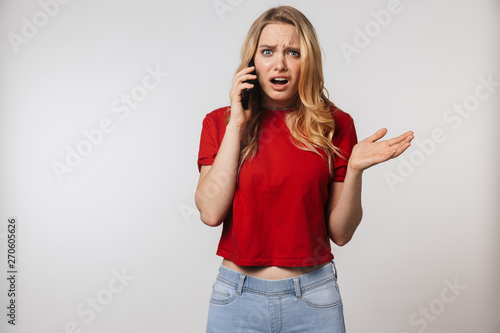 Confused young pretty beautiful woman posing isolated over white wall background talking by mobile phone.