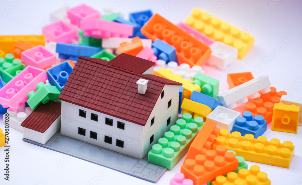 Real estate and new house construction concept: house scale model and multicoloured plastic construction toy building blocks or toy bricks. Selective focus