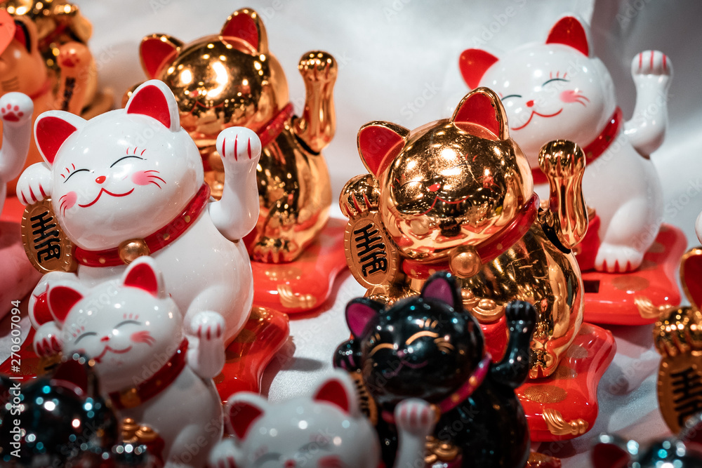 Fortune cats. Oriental souvenirs, mass produced for international export and trade. Close up shot, artificial lighting. Concept image for economic war between China and America. 