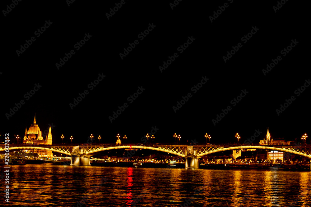 night Budapest, glowing in gold. The bridge over the Danube is illuminated by light bulbs. photo from the river