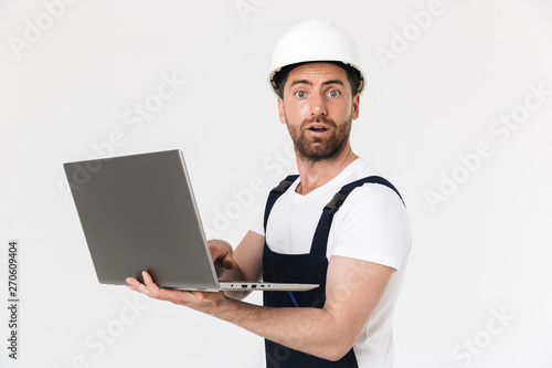 Confident bearded builder man wearing overalls standing