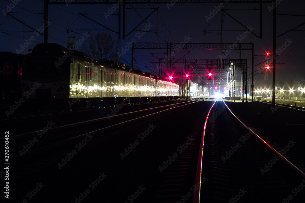A suburban train standing at night on a siding.