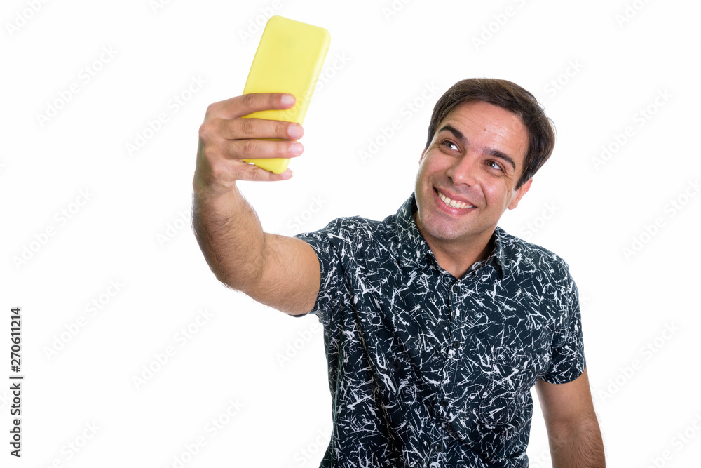 Studio shot of young happy Persian man smiling while taking self Studio shot of young happy Persian man smiling while taking self