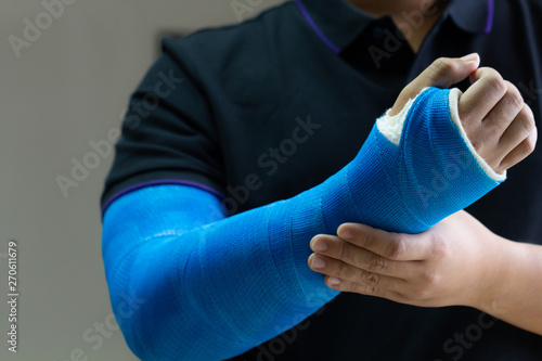 Close up man holding hand with blue bandage as arm injury concept.