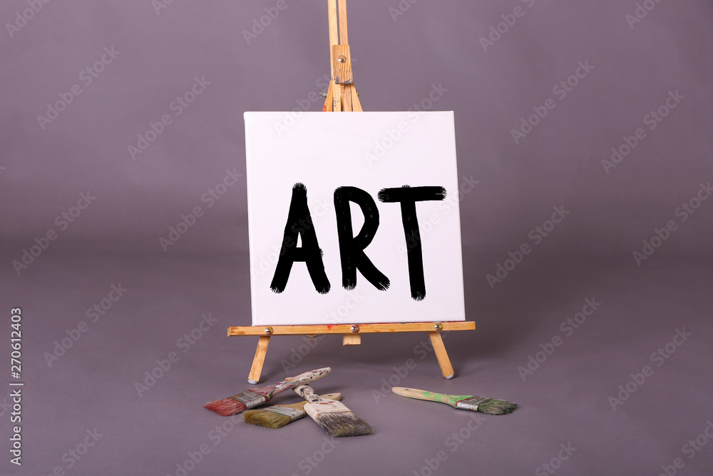 White Square Canvas With The Word Art Painted In Black Paint On A Painters  Easle Scattered Paint Brushes Stock Photo | Adobe Stock