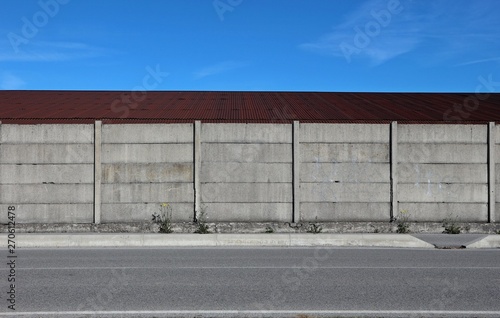 Wallpaper Mural Gray concrete wall, a tin brown roof with a road in front. Urban background for copy space Torontodigital.ca