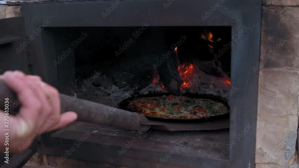 Chef getting Italian pizza out of rustic oven using large metal peel. Chef getting Italian pizza out of rustic oven using large metal peel.