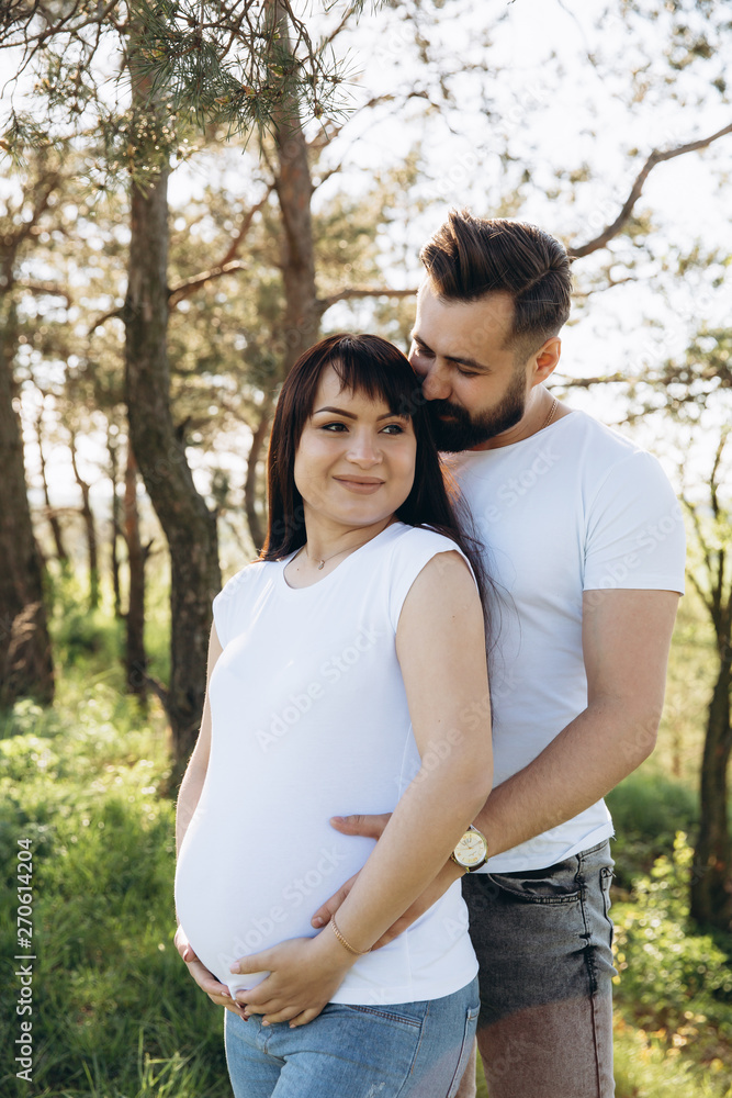 Pregnant woman and her beaeded husband hugging on the tummy together in nature outdoor Pregnant woman and her beaeded husband hugging on the tummy together in nature outdoor