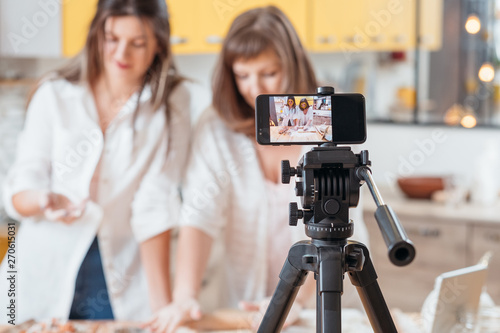 Culinary vlog. Two women baking shooting smartphone video tutorial. Content creating equipment. Online business hobby.