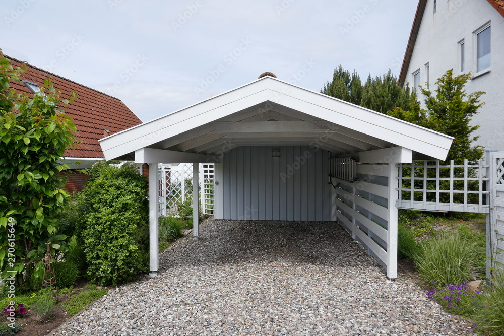 Wooden carport with pitched roof, white with open driveway on pebble floor next to a house. Germany, Europe - obrazy, fototapety, plakaty 