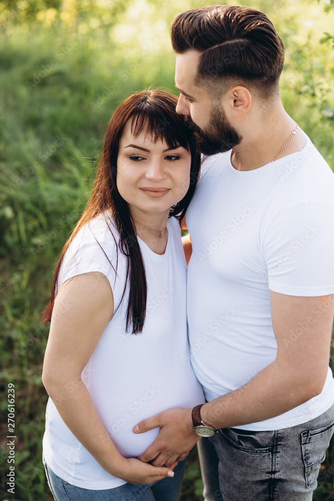 Pregnant woman and her beaeded husband hugging on the tummy together in nature outdoor Pregnant woman and her beaeded husband hugging on the tummy together in nature outdoor