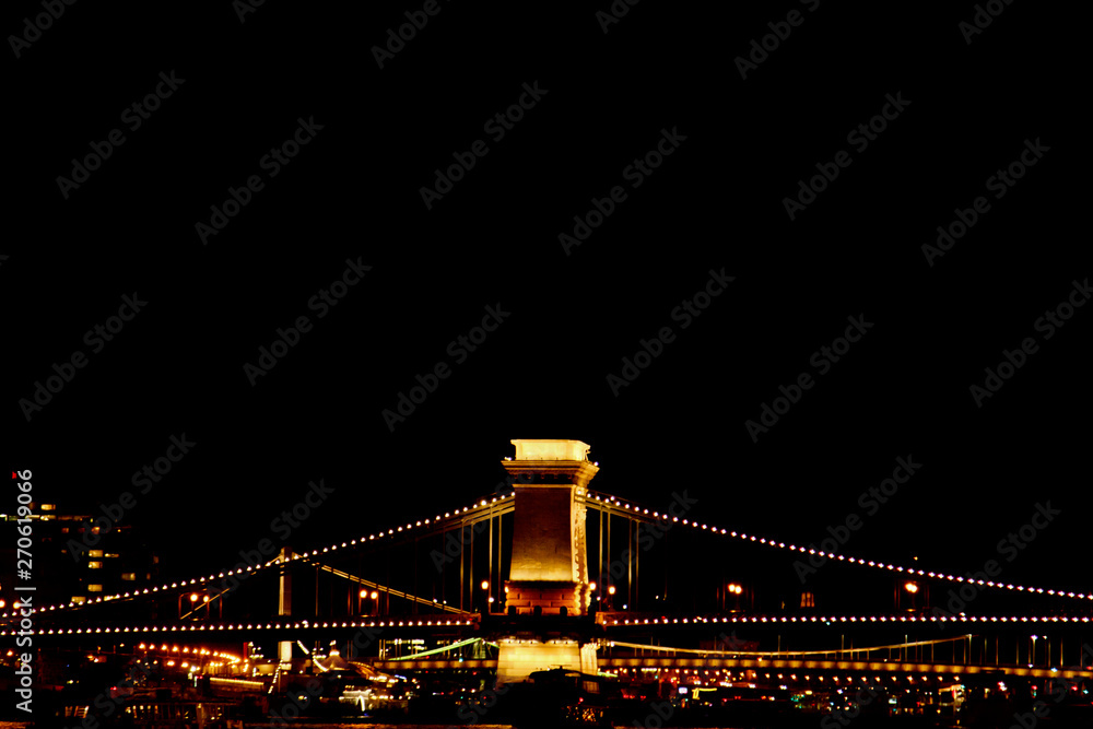 night Budapest, glowing in gold. The chain bridge over the Danube is illuminated by light bulbs. photo from the river