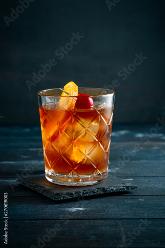 Whiskey sour cocktail with a slice of orange, cherry and ice, a classic alcoholic drink