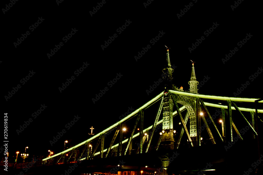 Obraz premium Budapest Hungary, 05.29.2019 glowing liberty bridge across the Danube River. night Budapest glowing in gold