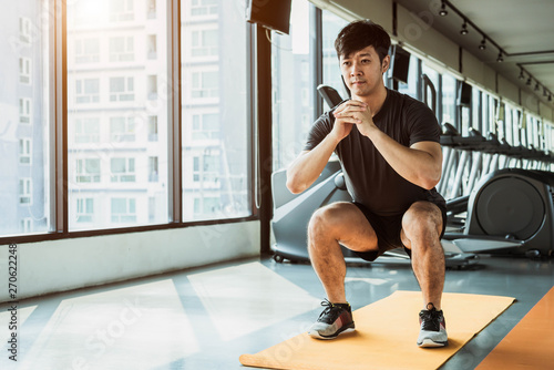 Foto Sport man doing squat posture on yoga mat in fitness gym at condominium in urban